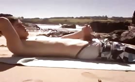 A gay surfer boy plays with his dick on a beach